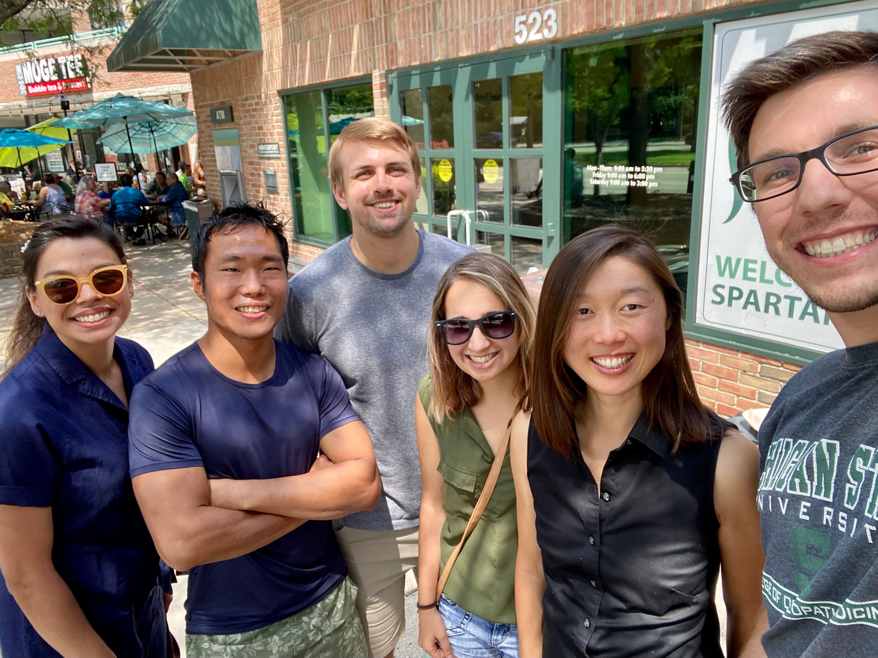 Group selfie photo outside businesses on grand river in east lansing 2021