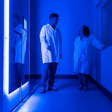 A blue-lit room with two researchers in lab coats