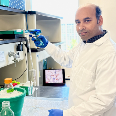 Dr. Rahman in lab coat and gloves