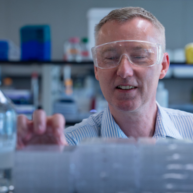BMB researcher in lab with goggles.