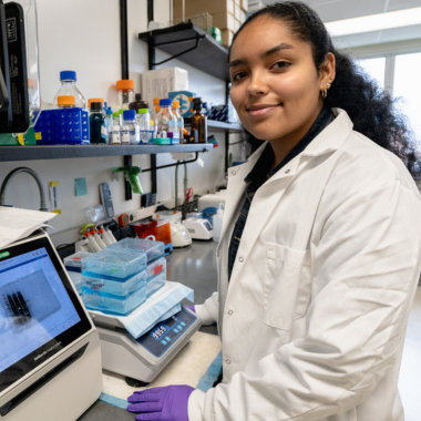 A BMB student poses in the lab in front of research instruments